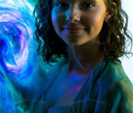 AI-generated abstract art of beautiful women gently enveloped in swirling translucent color mist, iridescent light shimmering on skin. By Jeff Dupler.
